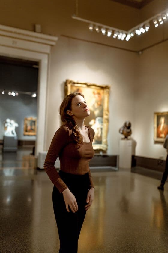 Visitor admiring paintings and sculpture in an art gallery