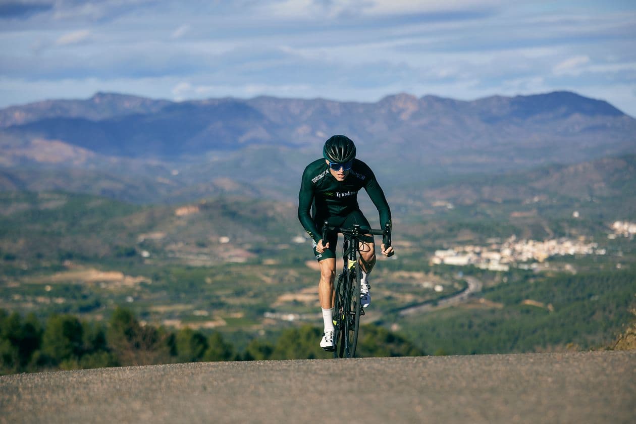 Road cyclist riding through a scenic mountain landscape