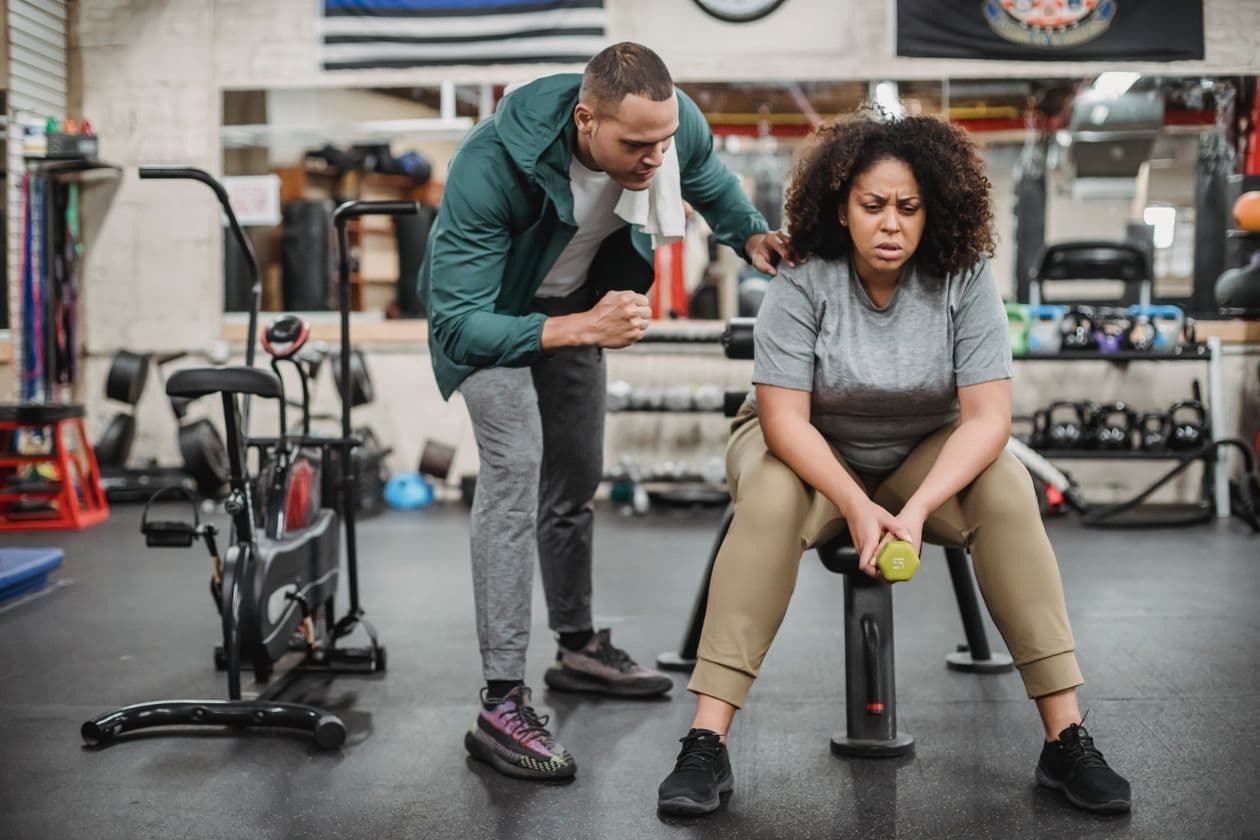 Fitness counselor encouraging a client during a dumbbell workout